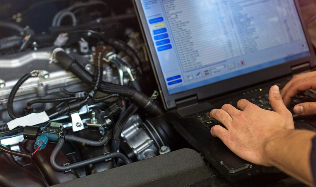 tech performing engine diagnostics on laptop