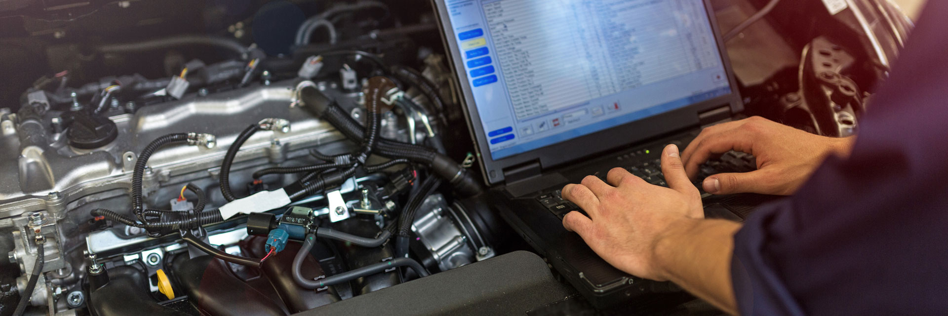 tech performing engine diagnostics on laptop